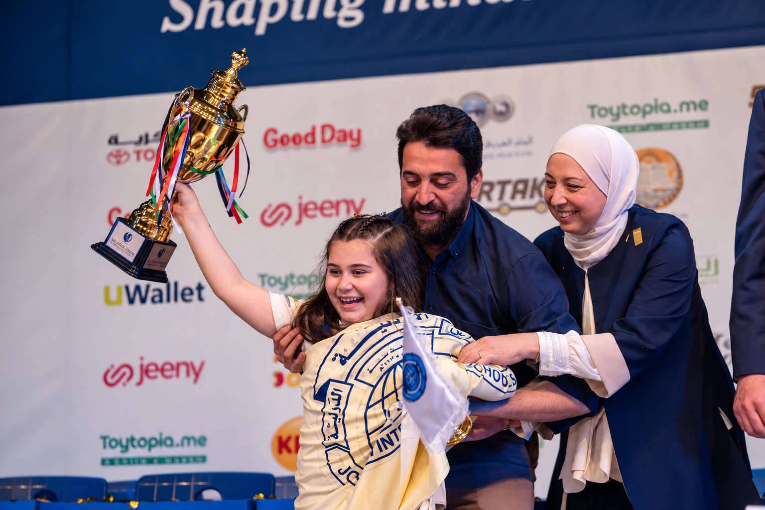 A child celebrating a Little Genius trophy with her family